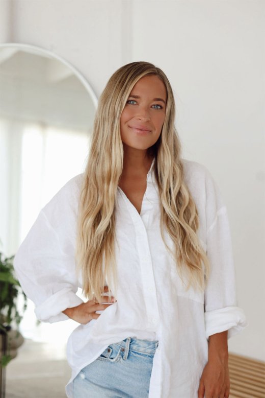 Jordan (The Balanced Blonde) wearing a white oversized shirt and light blue jeans.