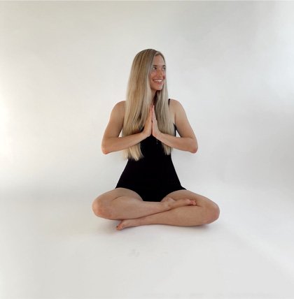 Jordan (The Balanced Blonde) sitting in the Sukhasana position wearing a black workout set.