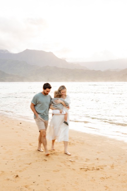 Jordan, her husband and baby walking on the beach.